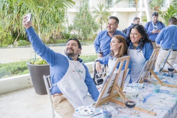 Adults enjoy a group painting workshop, capturing a fun selfie together.